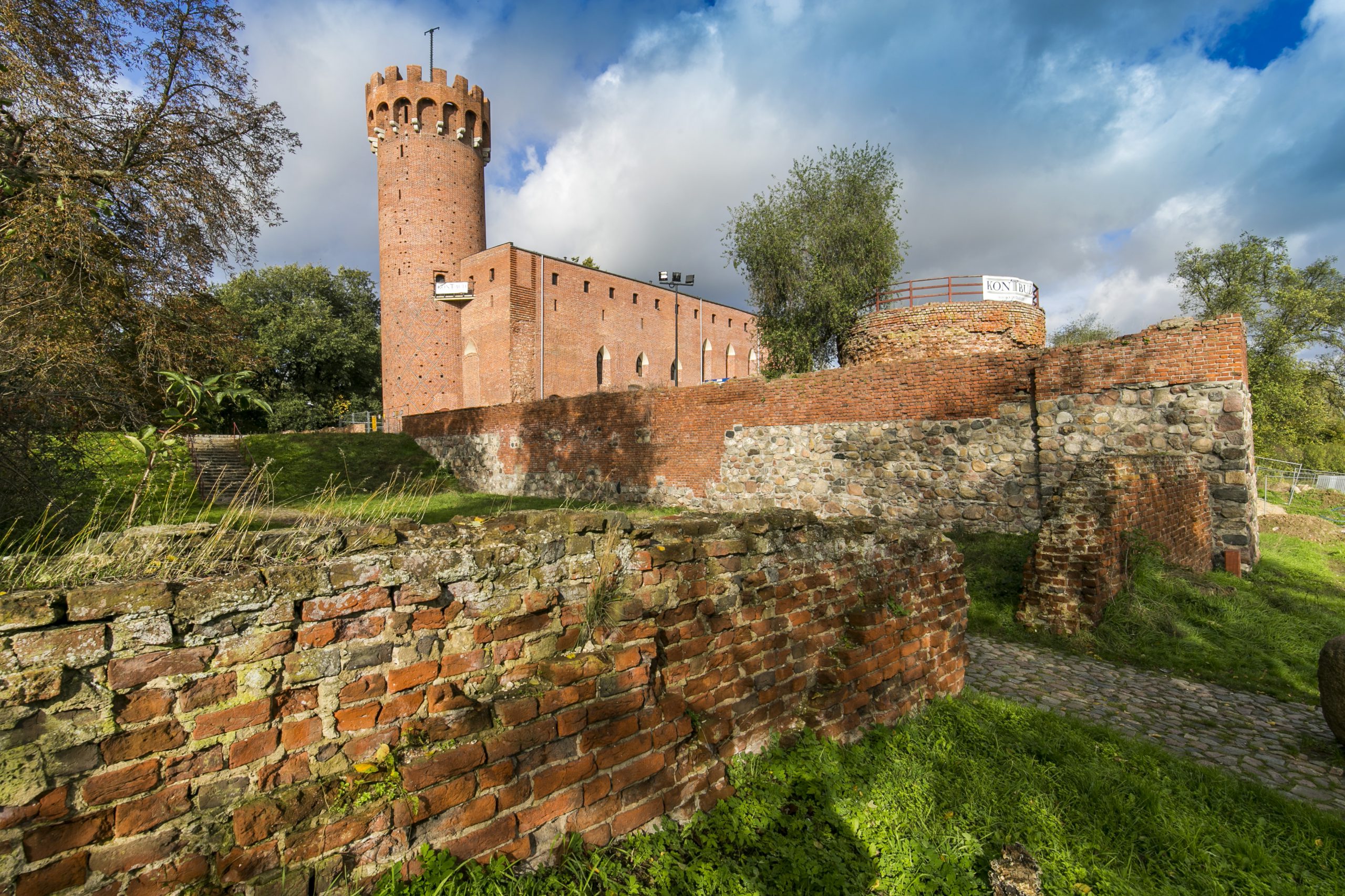 widok na zniszczony mur obronny zamku, w tle zamek krzyżacki w Świeciu