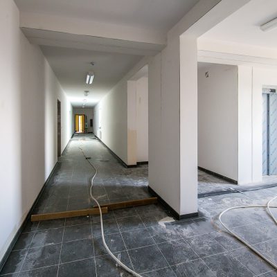 korytarz w domu z mieszkaniami chronionymi, po środku korytarza rośniagniety przewód elektryczny