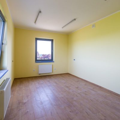 pusty pokój z żółtymi ścianami w domu z mieszkaniami chronionymi, na końcu pokoju okno