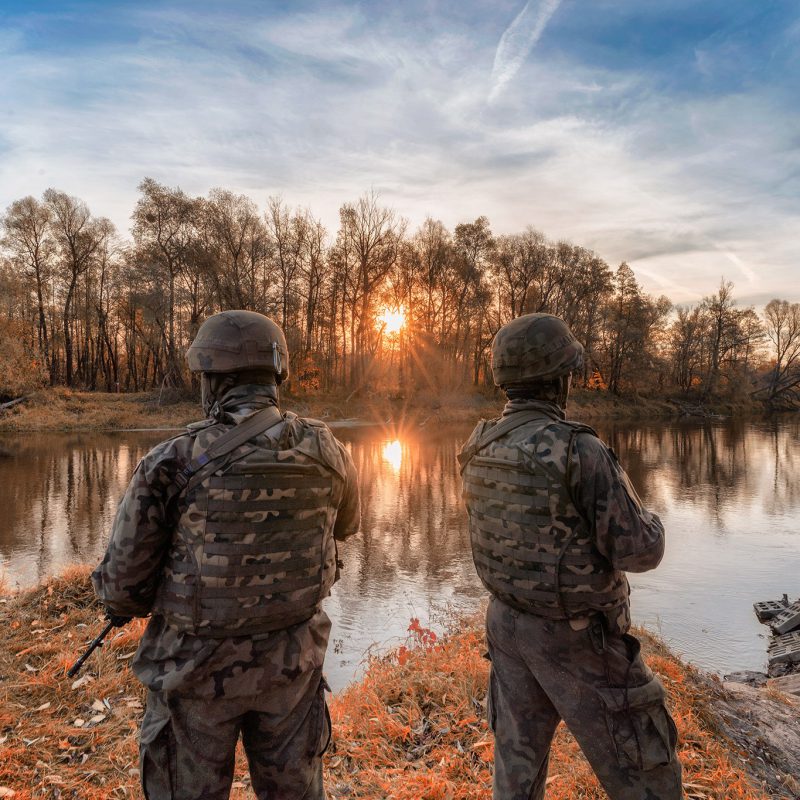 dwóch żołnierzy stojących nad jeziorem